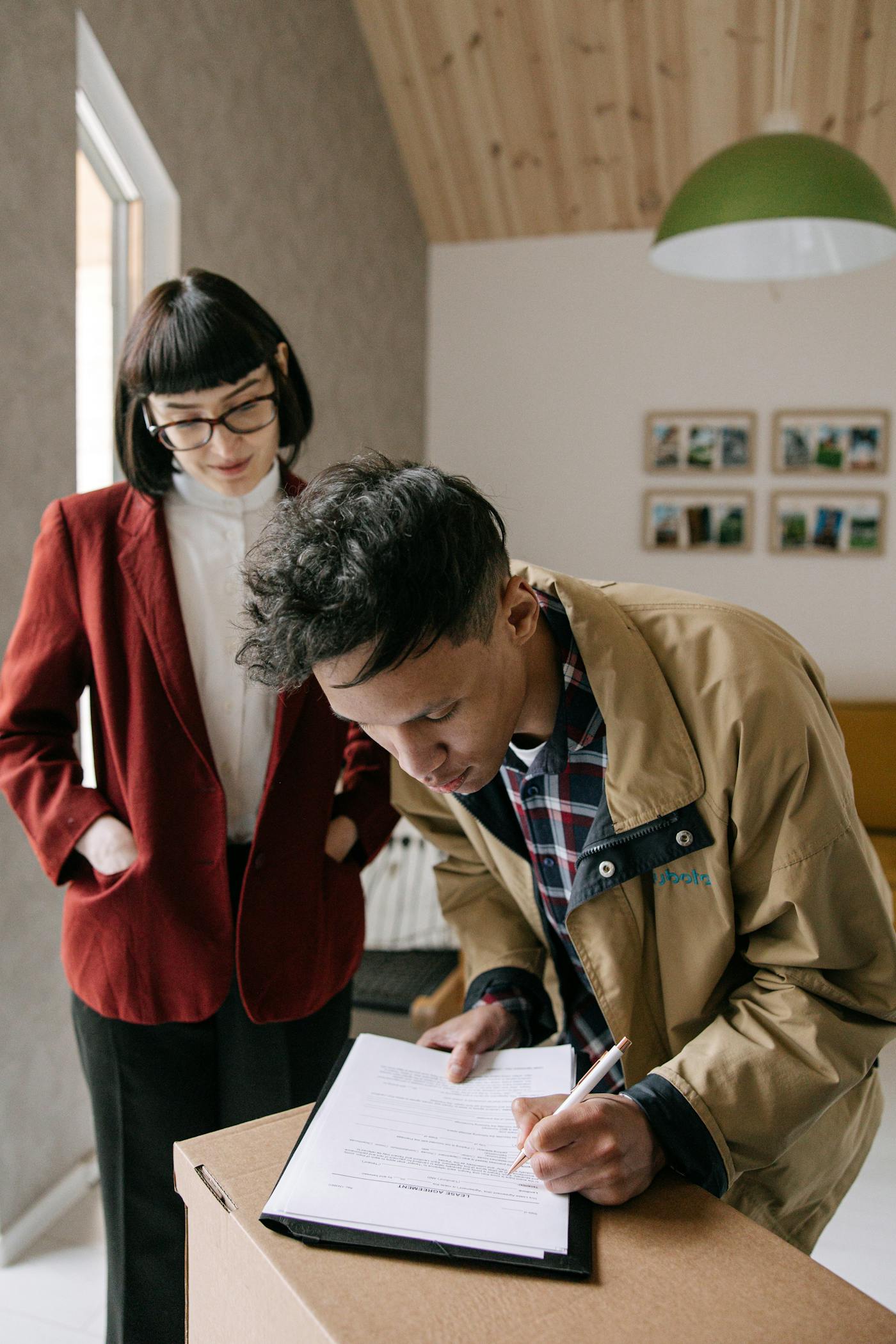 Buyer signing a closing contract while a representative looks on.